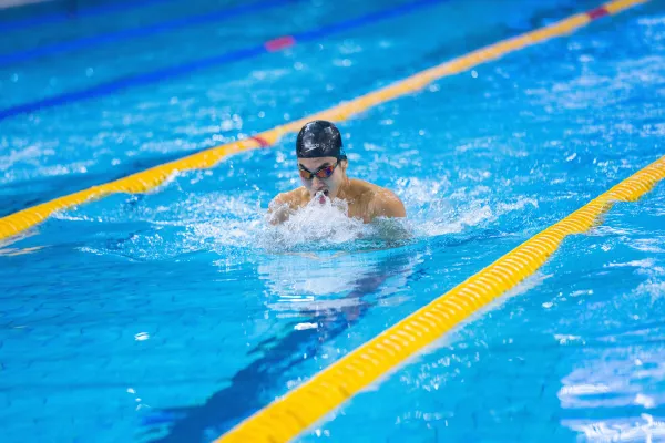 Nageur effectuant la brasse dans un couloir de piscine intérieure.