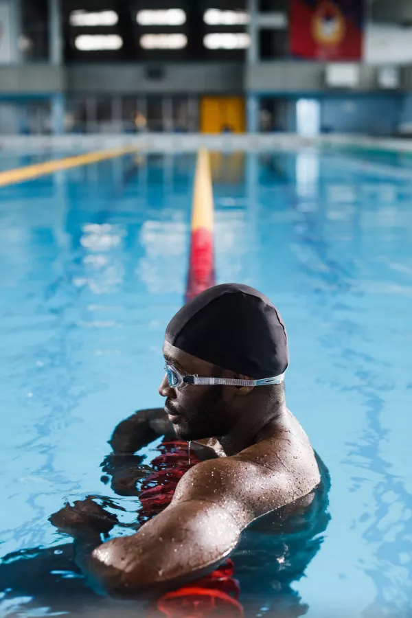 Nageur appuyé sur une ligne de couloir pendant une pause dans une piscine intérieure.