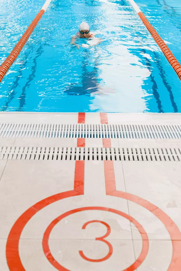 Nageur avançant dans le couloir 3 vers le mur d’une piscine intérieure.