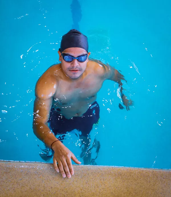 Nageur dans une piscine intérieure, prêt à reprendre une série d’entraînement.