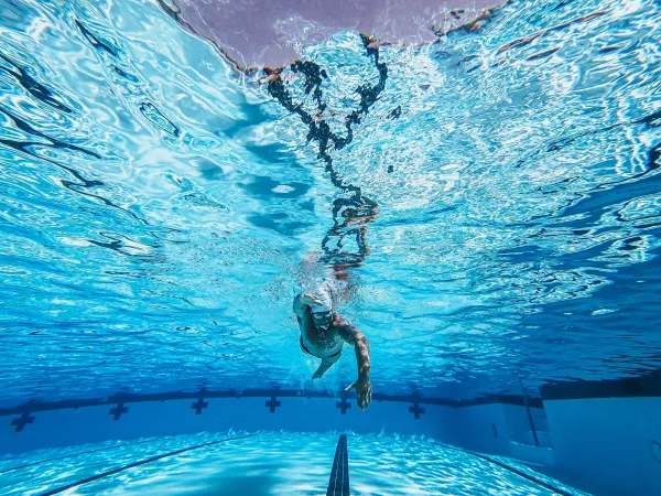 Nageur avançant sous l’eau dans une piscine, corps allongé.