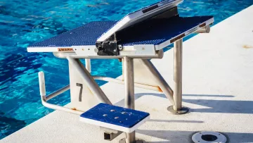 Bloc de départ numéro 7 au bord d’une piscine.