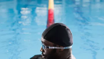Nageur appuyé sur une ligne de couloir pendant une pause dans une piscine intérieure.