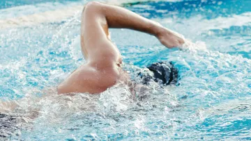 Nageur en crawl régulier dans une piscine extérieure.