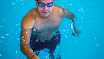 Nageur dans une piscine intérieure, prêt à reprendre une série d’entraînement.