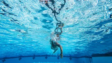 Nageur avançant sous l’eau dans une piscine, corps allongé.